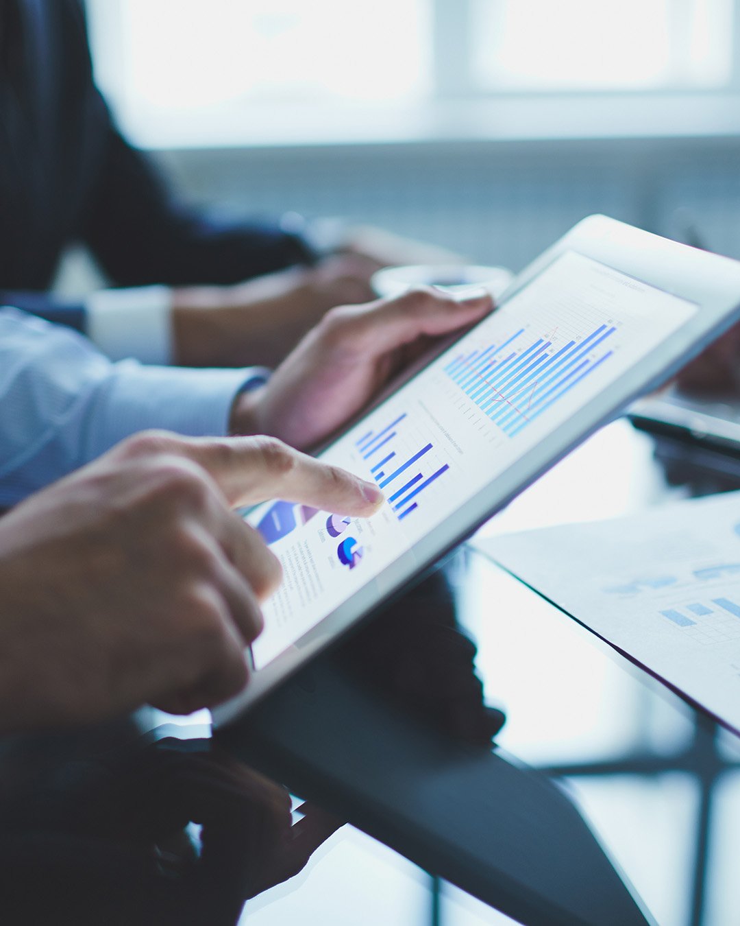 Imagen mostrando a un hombre usando una tablet y viendo gráficos de estadísticas y datos.